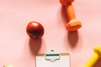 10 Longevity-Tipps: So bleibst du fit bis ins hohe Alter Äpfel, Hanteln und ein Klemmbrett mit Zettel; Symbolbild, Longevity, Credit: Alesiakozik via pexels